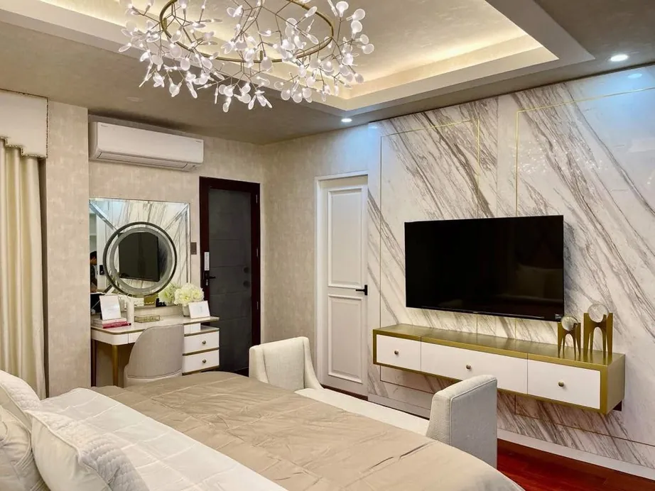 Wall-mounted white media console with brushed brass frame under a marble feature wall