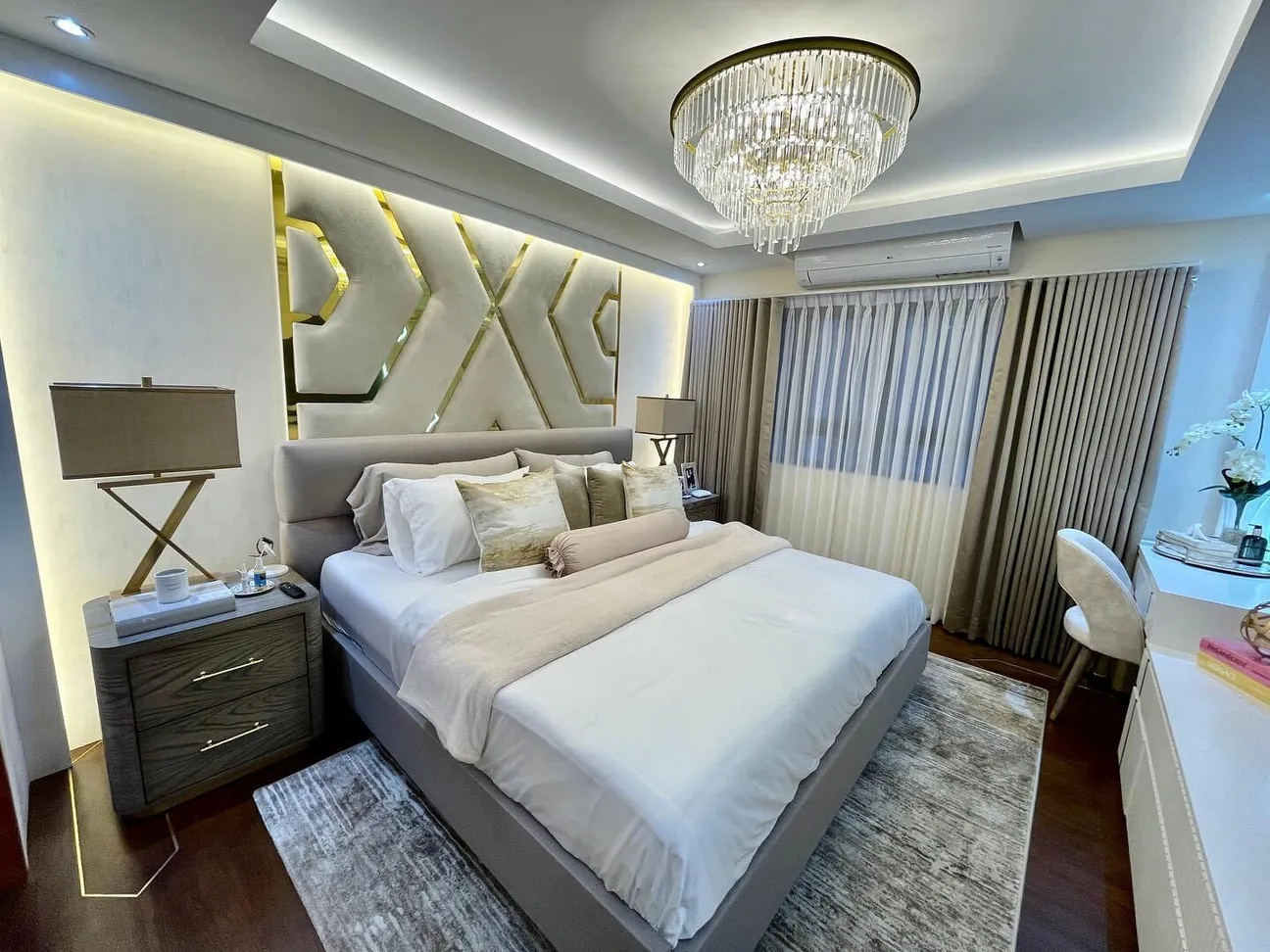 Upholstered headboard wall with geometric brass inlay behind a grey platform bed