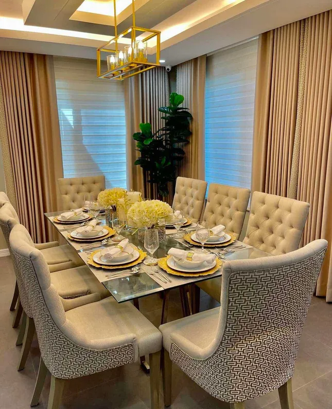 Glass-top dining table with button-tufted cream chairs and patterned host chairs