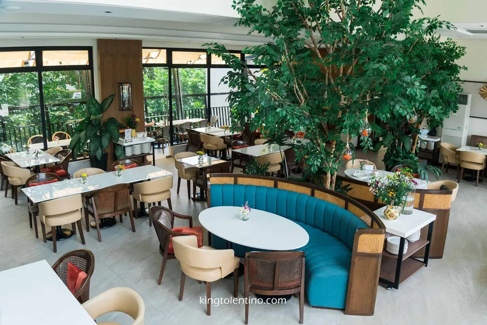 Teal channel-tufted curved booth wrapped around an indoor tree at Girasol Tagaytay